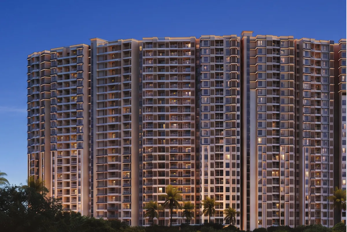 Prestige Parklane residential towers lit up at dusk above a line of palms and trees