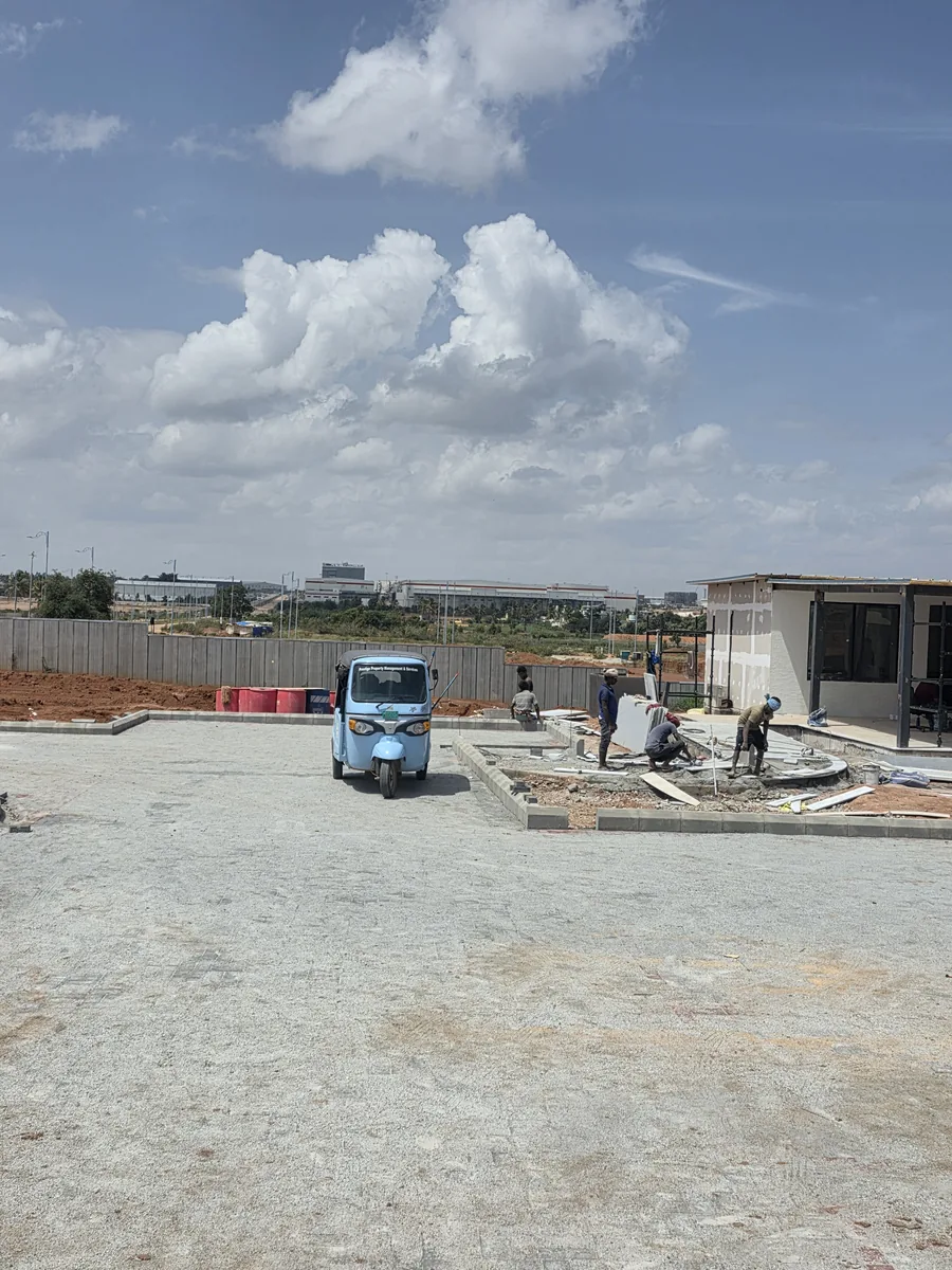 Workers laying a circular landscape feature beside the experience centre pavilion at Prestige Park Lane, KIADB Aerospace Park Phase 2, Devanahalli, August 2026
