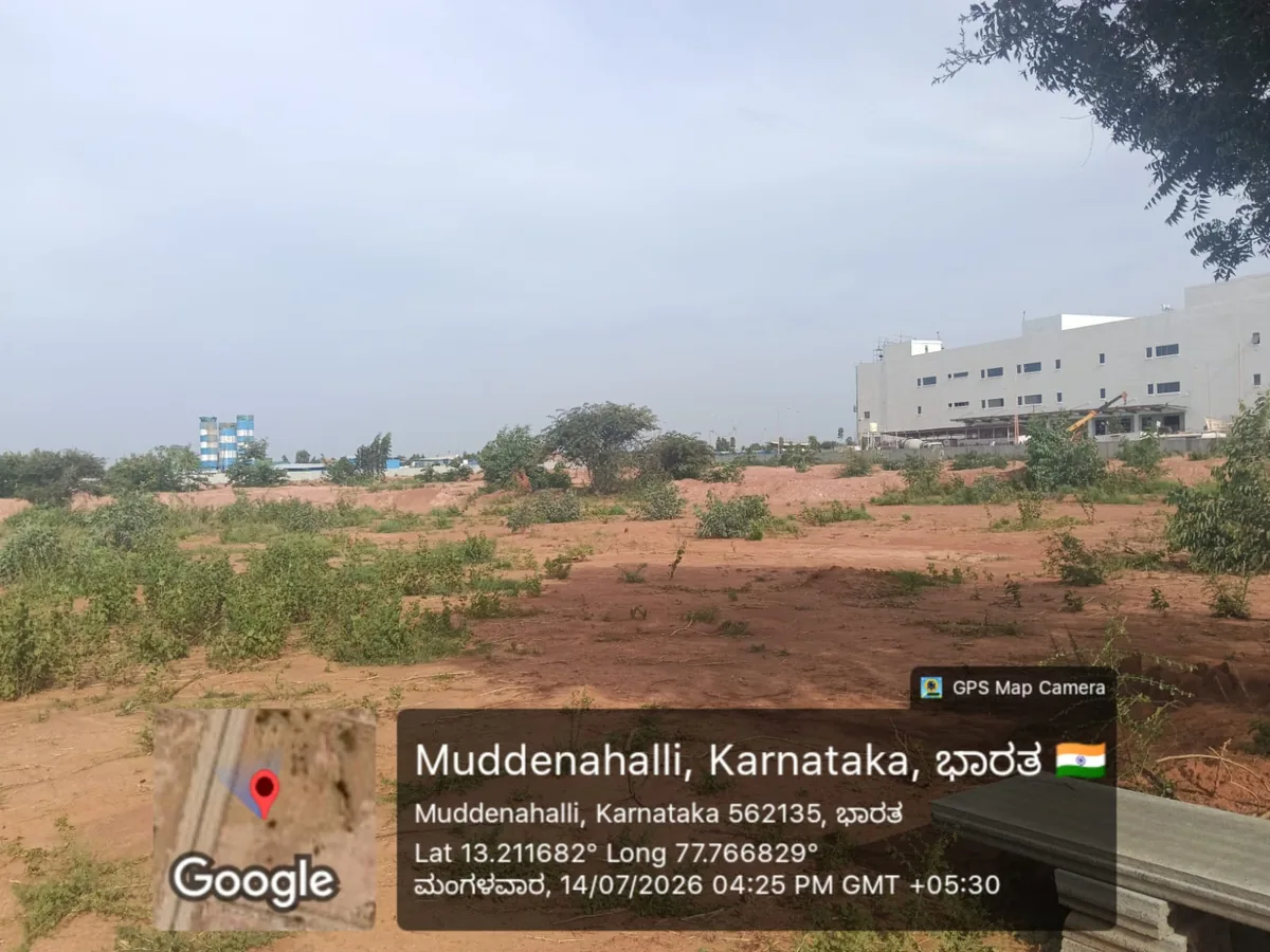 Cleared and levelled land at the Prestige Parklane site in KIADB Aerospace Park Phase 2, Devanahalli, with the operating KIADB industrial estate behind, photographed 14 July 2026